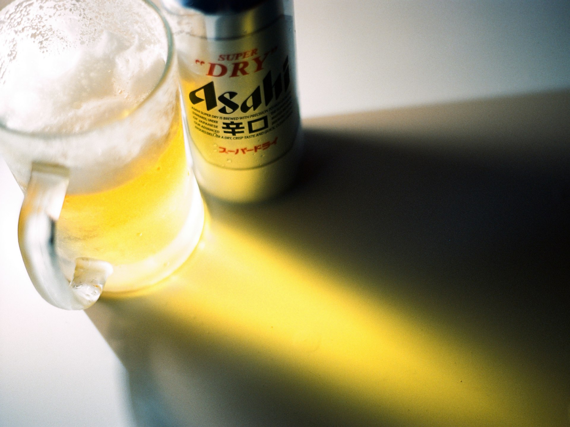 A mug of beer and an asahi can.