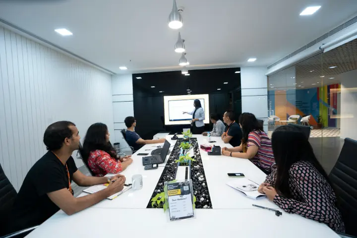 people sitting at the table looking to another person standing in front of them