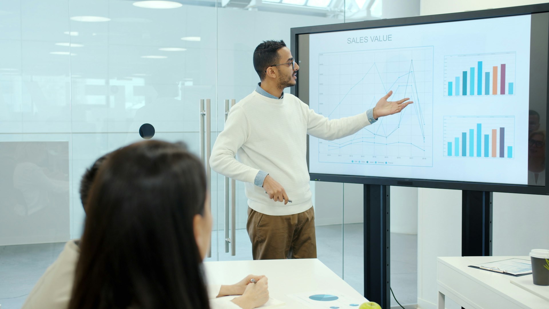 Man presenting charts on a large screen.